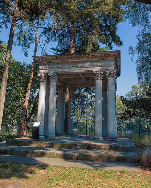 Mexico City CDMX Mexico 10 11 2022 Neoclassical monument with white pillars in Chapultepec forest Mexico City with a lake in the background and a lighted sign reading My God does not, blending history culture and urban landscape.