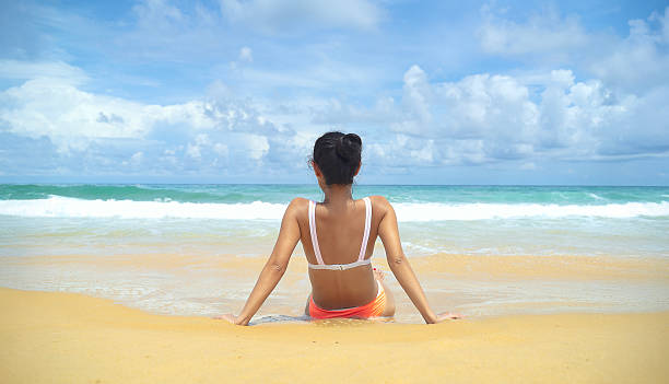 Rear view of woman in bikini standing against the beach in summer