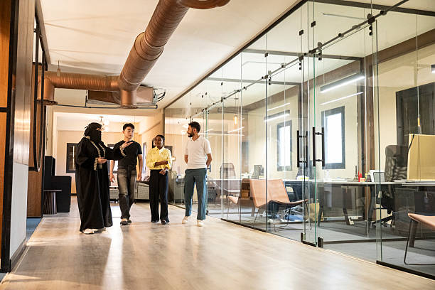 istock Four multiracial colleagues walking through in modern commercial building, talking 2231538047
