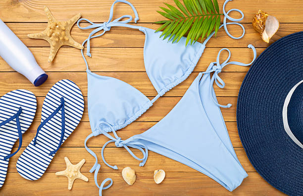 istock Blue bikini with beach accessories on wooden background, top view 2231540051