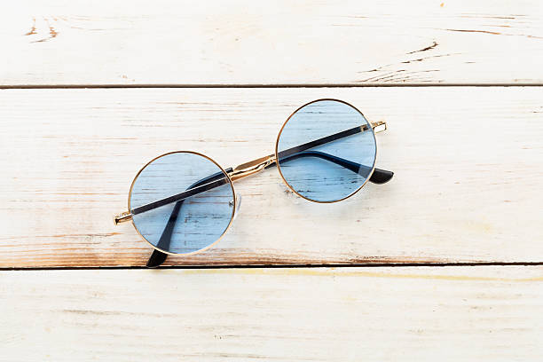 Blue sunglasses on wooden background, top view