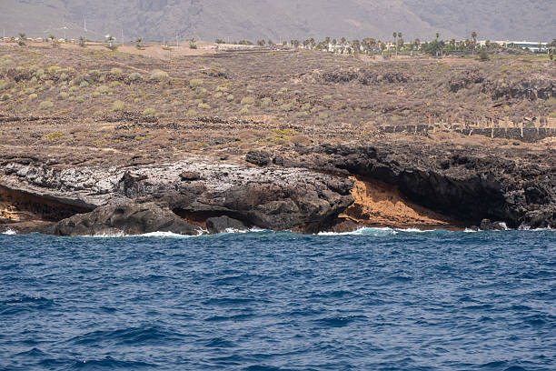 Rugged coastal cliff with blue ocean waves and rocky landscape horizon.