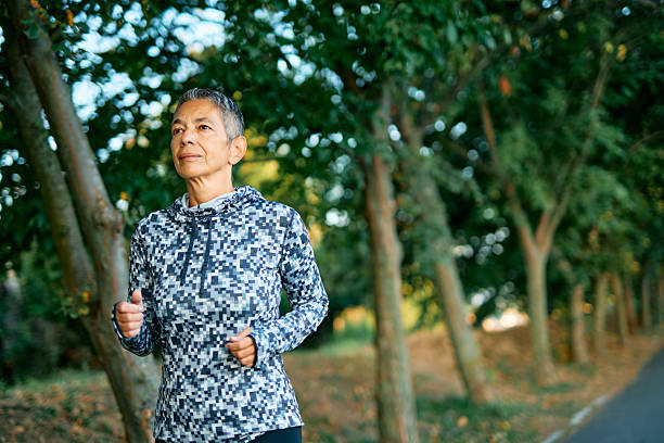 istock Senior woman jogging in a tree-lined park enjoying exercising 2231546063