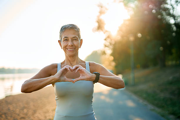istock Senior woman making heart shape with hands while exercising outdoors 2231546135