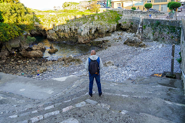 A man gazes at a small cove in Castro Urdiales, Cantabria, Spain.