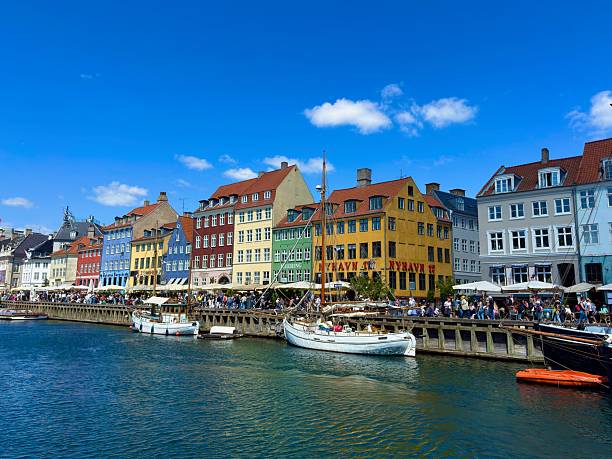 Copenhagen, Denmark : July 3, 2025 - Nyhavn ia a 17th-century waterfront, canal and entertainment district in Copenhagen, Denmark.The colorful houses of Nyhavn are one of the most iconic sports  with restraints along the canal.