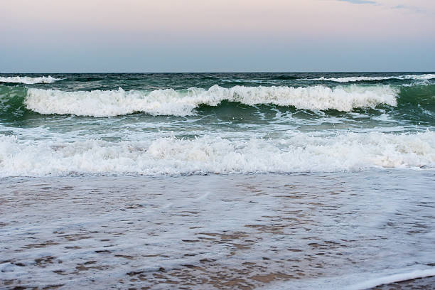 istock Strong ocean waves breaking on sandy beach at sunset 2231554222