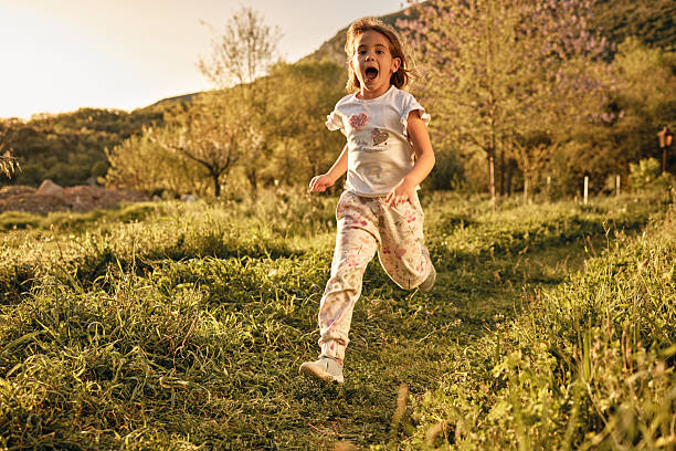 Happy girl running through the field on a sunset.
