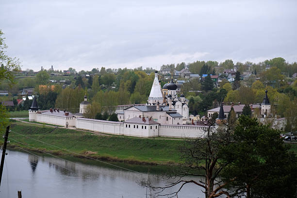 istock Historic monastery overlooks serene river with lush greenery and charming village in background during cloudy day 2231604502