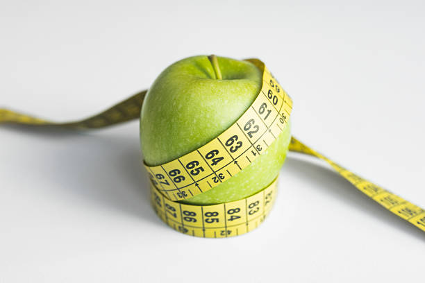 Green apple with measuring tape for sport, fitness, diet concept