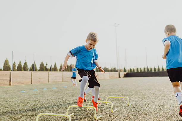 istock Group of boys jumping obstacles during training on soccer field 2231606100