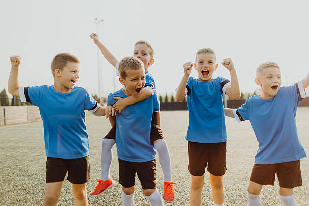 istock Junior soccer team posing together on the field in blue uniforms 2231606463