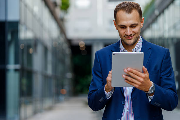 istock Professional working professional smiling, navigating digital tablet near sleek urban office, representing modern business connectivity 2231612860