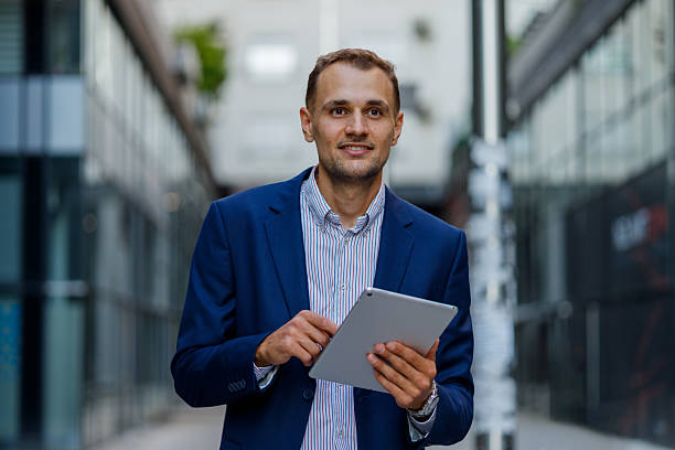 istock Young businessman walking confidently through the city, using a digital tablet to stay connected and engaged with work and information 2231613169