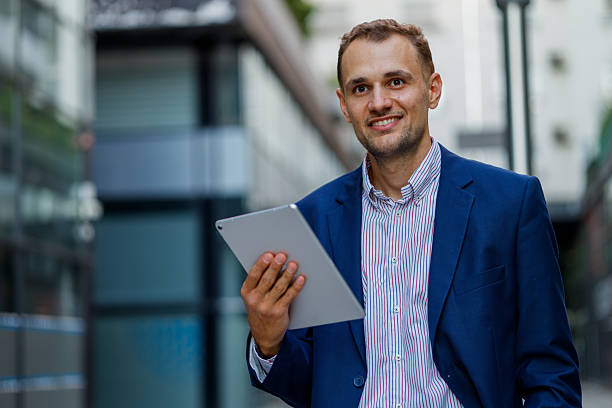 istock Young businessman smiling while using a digital tablet in a vibrant urban environment, exuding confidence and professionalism 2231613273