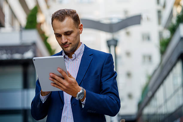 istock Professional businessman navigating urban landscape, working on digital tablet while walking through busy downtown street 2231613523