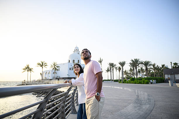 istock Curious couple looking up the sky while standing by railing along scenic Jeddah Corniche waterfront 2231614071