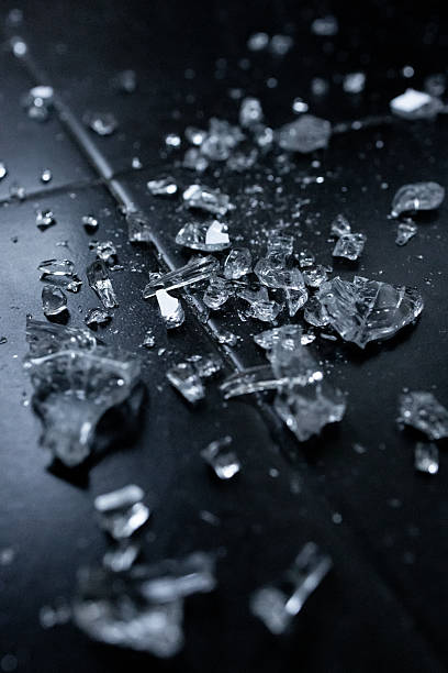 istock Shattered glass pieces scattered on black surface in low light 2231617466