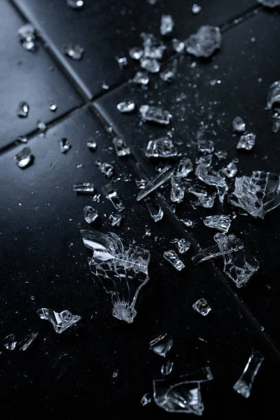 istock Close up of broken glass shards on dark tiled floor 2231618254