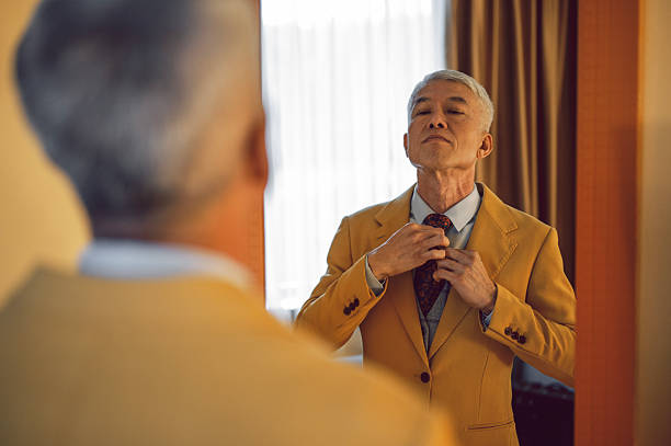 istock Senior Asian Businessman Adjusting Tie While Looking in Mirror 2231618274