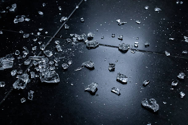 istock Shattered glass on black tiled floor with reflective surface in low light 2231618410
