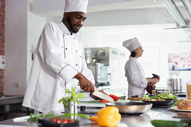 istock Black head chef chopping a fresh bell pepper in a modern workspace 2231623232