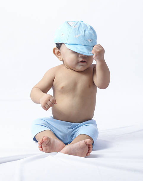 istock Baby boy adjusting blue cap while sitting indoors. 2231623694
