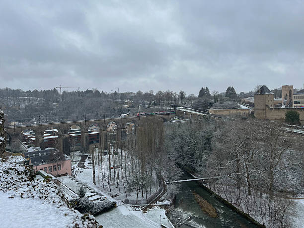 Panoramic view of the Grund district covered in snow during winter, highlighting the train bridge over the Alzette River. Luxembourg 2023-01-20