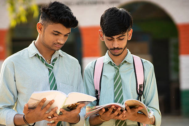 istock Two teenage school students studying on book together and discussing about studying by looking at the book. 2231645875
