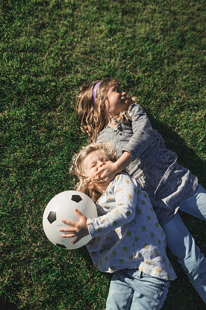 istock little sister having fun on the grass 2231650088