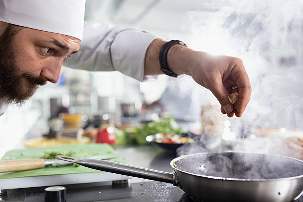 istock Professional chef perfects a gourmet dish by adding fresh herbs in kitchen 2231652891