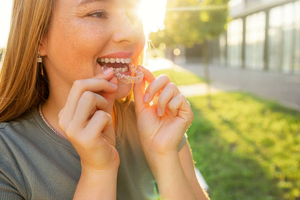 istock Woman smiling while applying clear aligners in a sunny outdoor setting 2231653736