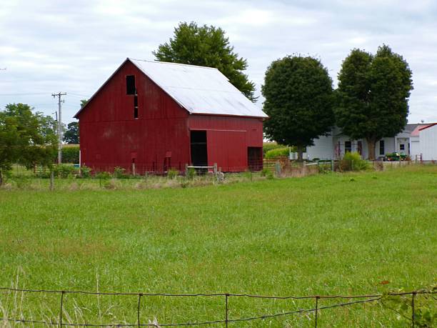 Red barn in pasture on cloudy day.