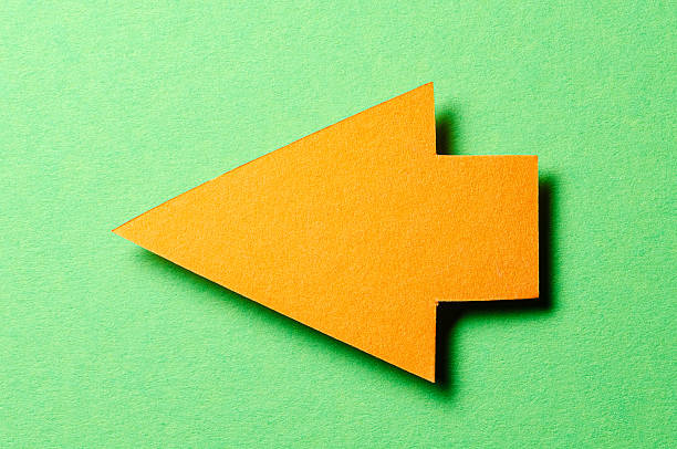 istock Orange cut out blank paper cardboard arrow direction sign with copy space for text on green background, flat lay top view pointing symbol conceptual message backdrop 2231658687