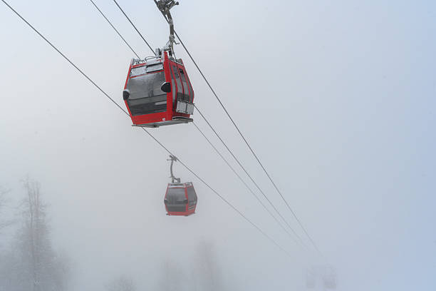 Red cable car cabins with. Cable car in the fog. A mysterious winter landscape.