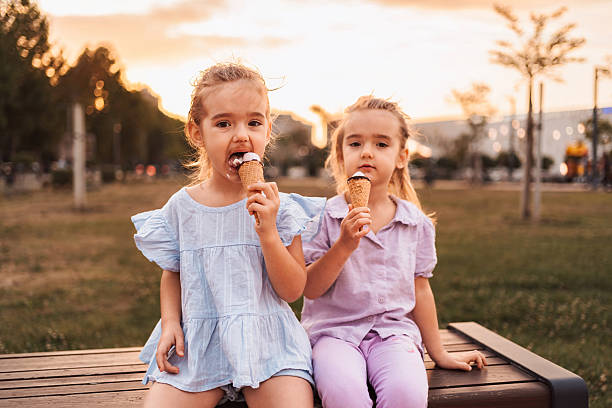 istock Two sisters enjoying ice cream cones in a park at sunset 2231666187