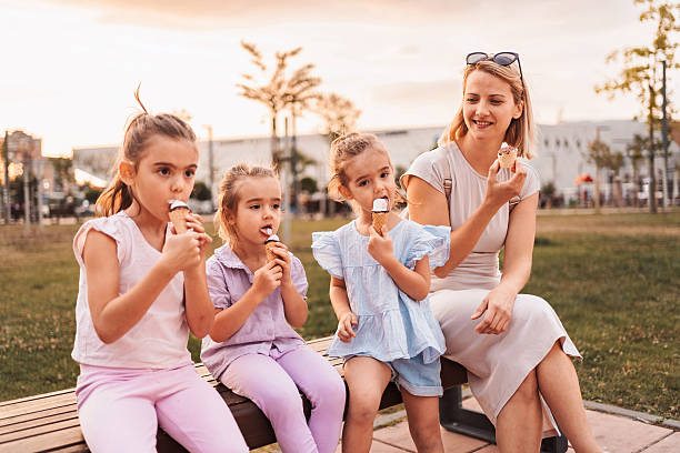 istock Mother and daughters enjoying ice cream cones in a park 2231666331