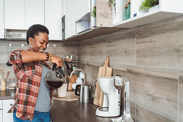 istock Young woman pouring coffee in her modern kitchen 2231666344