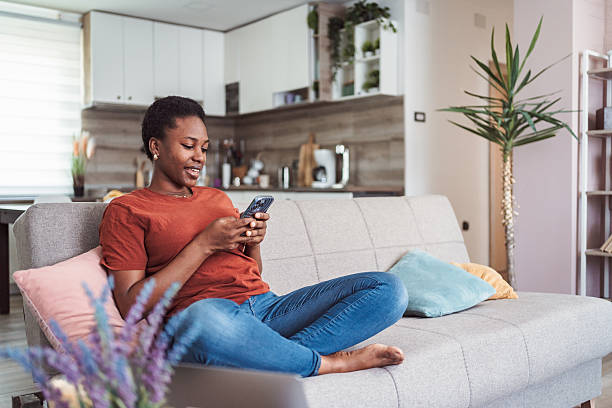 istock Young Woman Relaxing on Sofa Using Smartphone at Home 2231666429