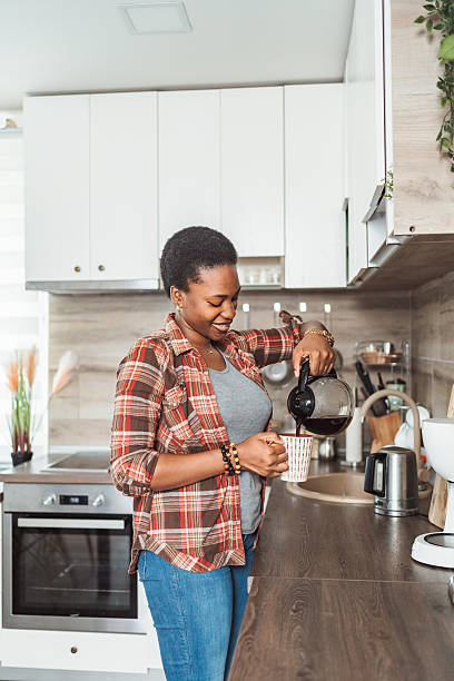 istock Young woman pouring coffee in her kitchen 2231666439