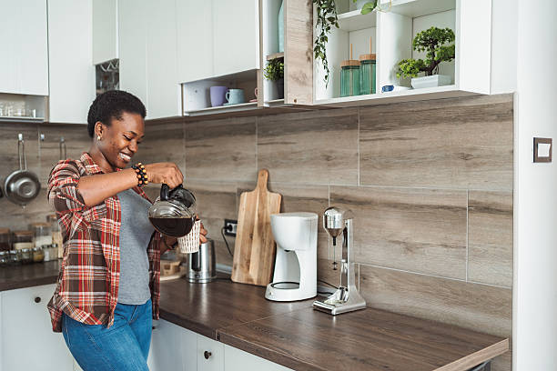 istock Young woman pouring coffee in a mug in her kitchen 2231666633