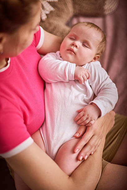 Young asian mother embrace of little baby girl with tender on bed in the bedroom, mom love newborn and care, woman with expression with child together, parent and daughter, family concept.