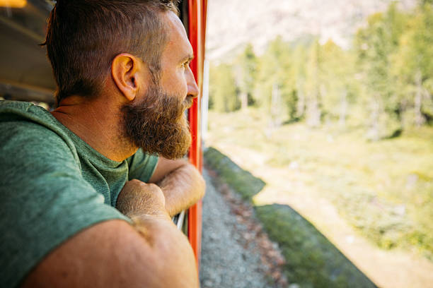 istock Man Watching Yellow Train Travel Through Mountains 2231667492