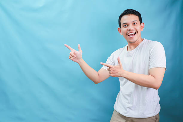 istock Joyful Young Man Pointing Enthusiastically Against a Light Blue Background in a Studio Setting 2231668506