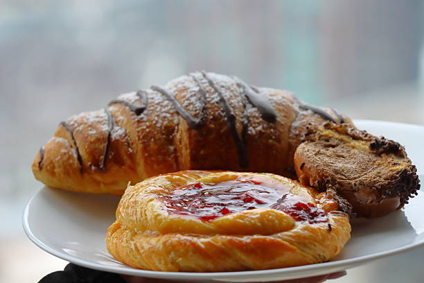 Freshly baked croissant and bun served on a clean white plate. Minimalist breakfast composition highlighting baked goods, morning meals, and cozy culinary moments.