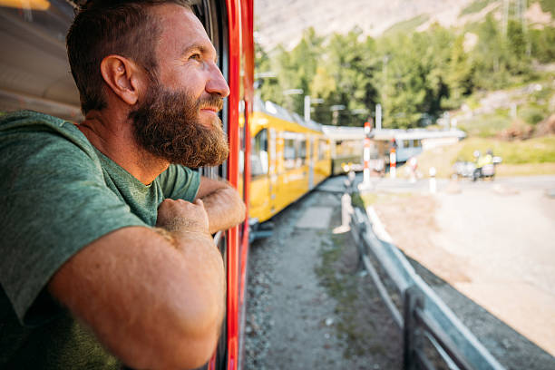istock Man Watching Yellow Train Travel Through Mountains 2231669886