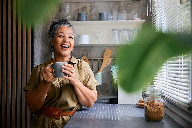 istock Happy senior woman laughing while drinking coffee in kitchen 2231674719