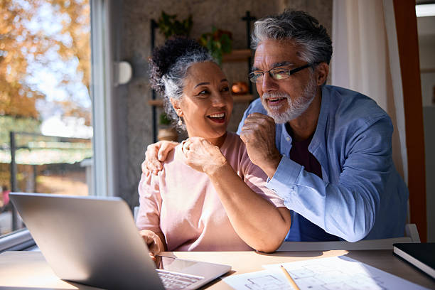 istock Happy senior couple using laptop at home, looking at blueprints and smiling 2231674913