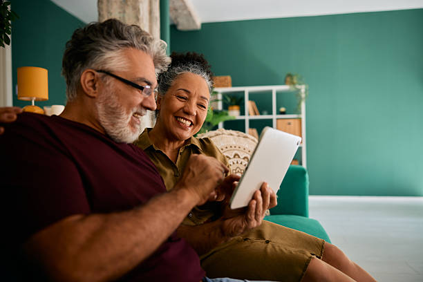istock Happy senior couple using digital tablet at home, smiling and browsing internet 2231675060