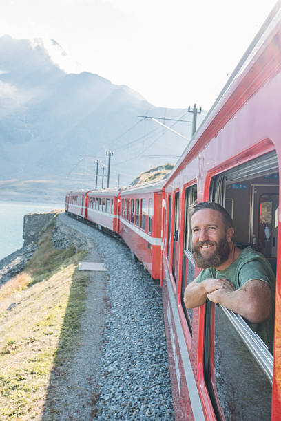 istock Man Looking Out Red Train Window Scenic Mountains 2231676407